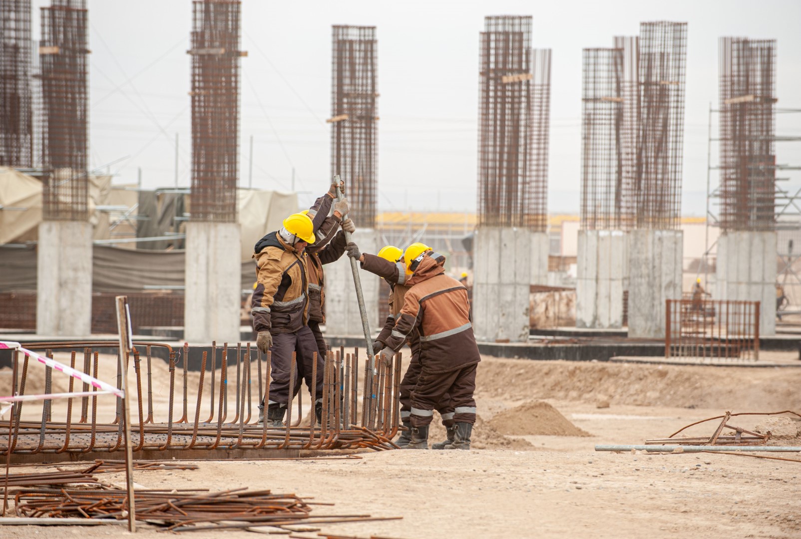 Workers in special equipment and yellow helmets with factory construction in the background